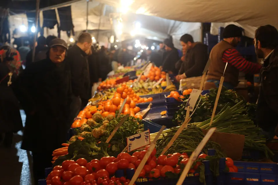 İstanbul'da akşam ışıklarında bir semt pazarında portakal, domates ve yeşillik tezgâhları
