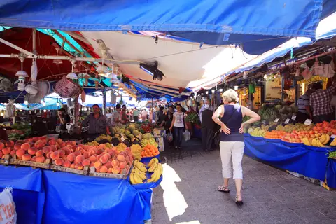 Bursa'da mavi tenteler altında meyve tezgâhları ve alışveriş yapanlar