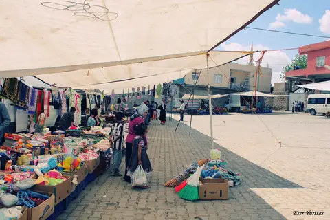 Tente altında giyim ve ev tekstili tezgâhlarının dizildiği haftalık pazar